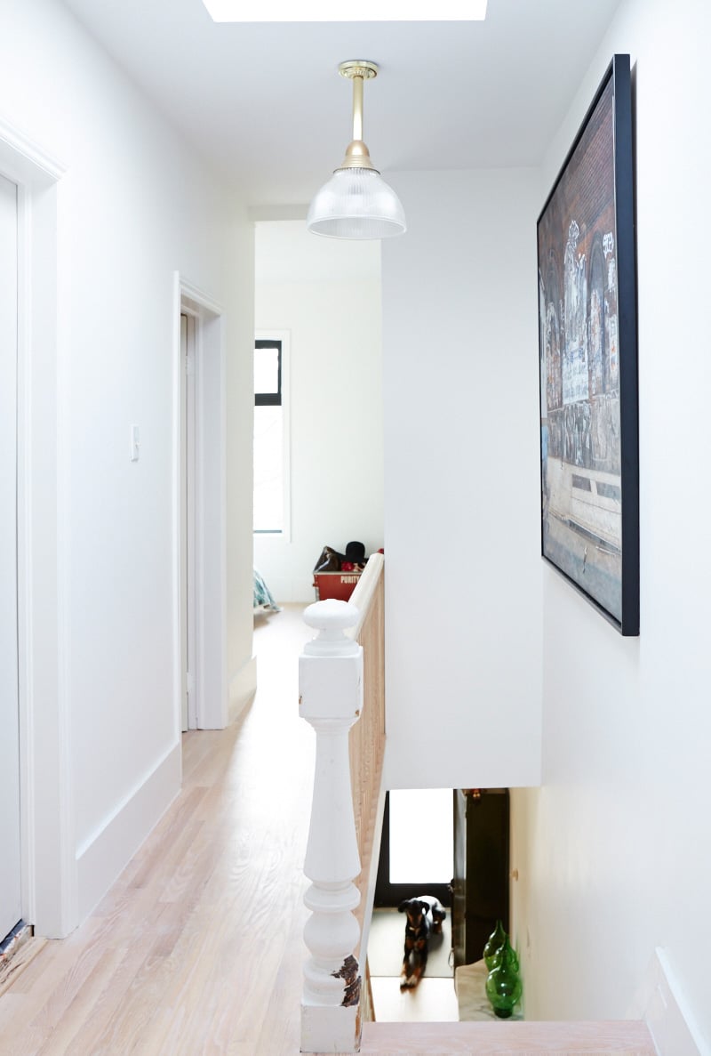 Stairs coming up to a second floor hallway in a narrow home in Toronto
