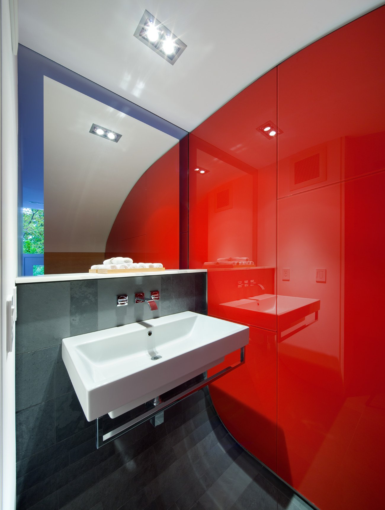 modern home Toronto - first-floor washroom is defined by a curved ceiling and floor, as well as a red wall - Kohn Shnier architects