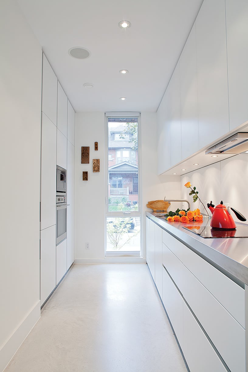 A white galley in a narrow modern house in Toronto, roses are visible on the counter