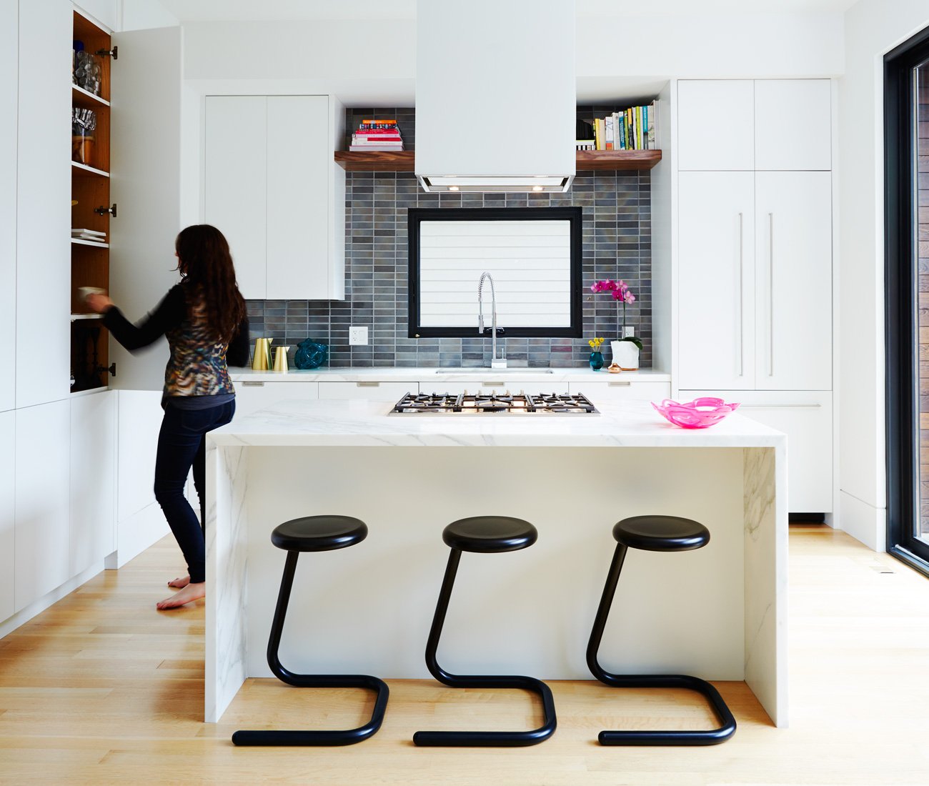 designer Alanna Davey - A female person is storing items in the kitchen cabinets. | Kitchen design Ideas