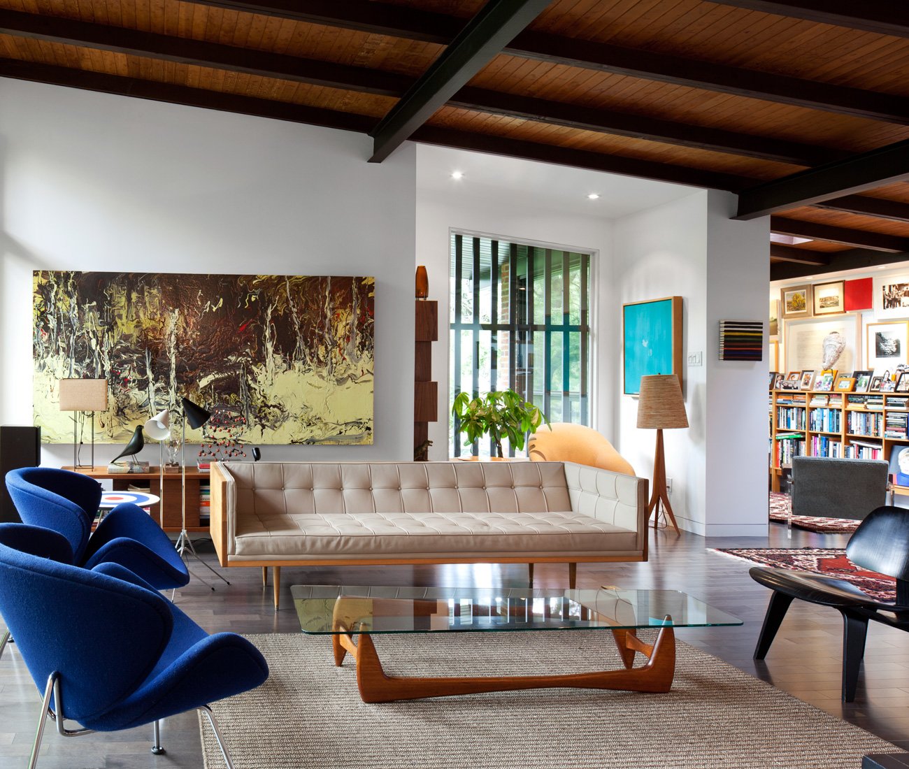 Living room of mid-century modern bungalow in Toronto renovated by LGA Architectural Partners, chairs, couch and coffee table are in foreground while arts is present on the house walls.