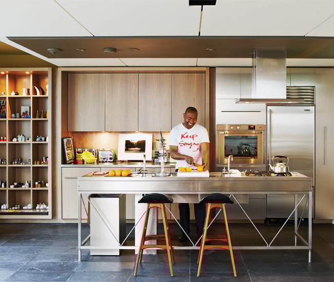 A male person is cutting oranges on a very industrial style stainless steel kitchen island