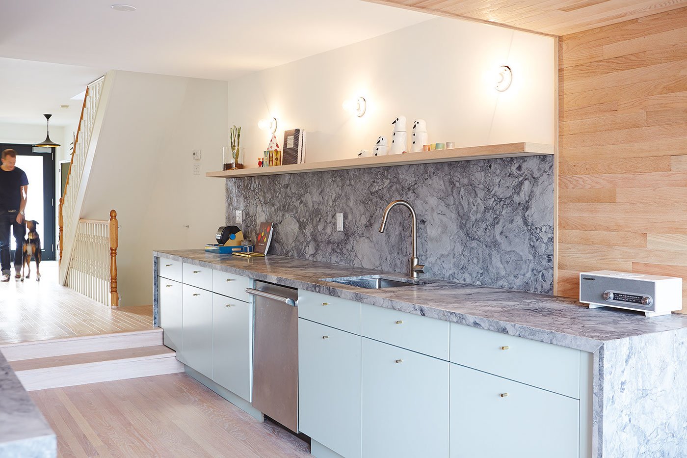 A male person (Matt Carr) with a dog is walking on the hardwood floor toward the kitchen || Kitchen design Ideas