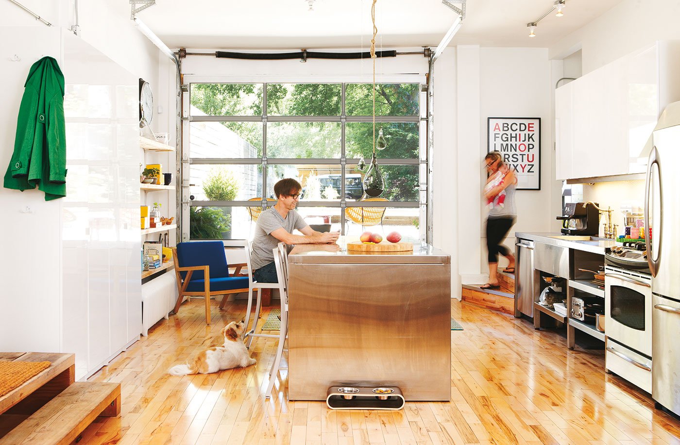 A couple is having some family time. The female person is holding a baby, the family dog is paying attention to the male | kitchen design ideas