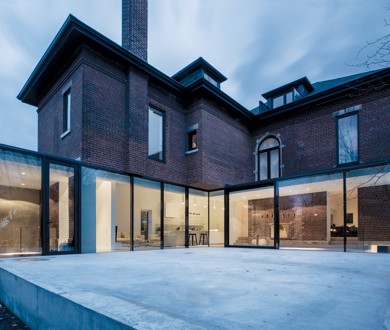 An L-shaped glass wing wraps around the back of the Edwardian house, merging gh3’s Modern Interior Design with classic architecture and surrounding a plinth-like patio. - Architect Pat Hanson