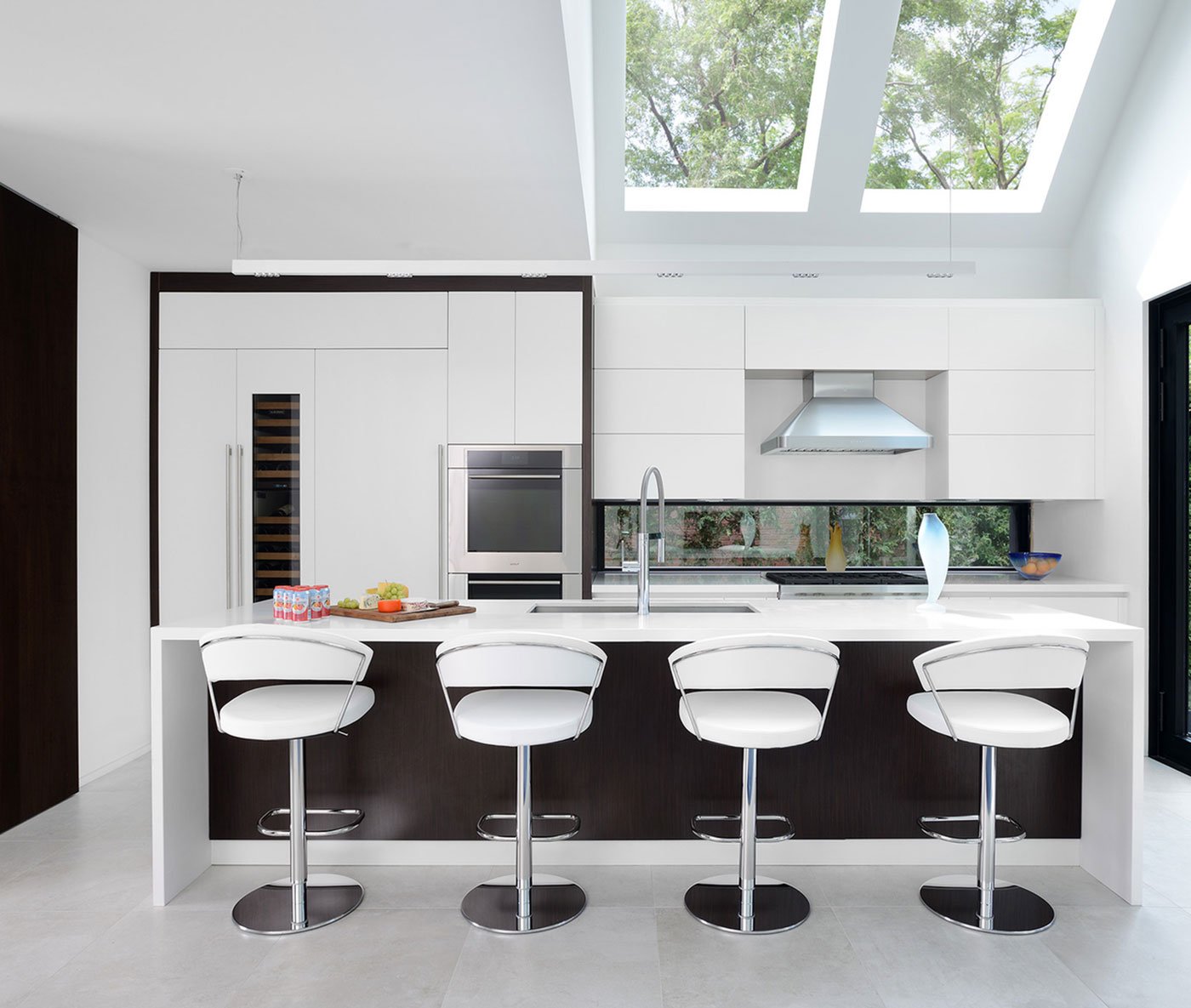 White kitchen with a Long Island and four stools, skylights over the kitchen - Yorkville Design Centre