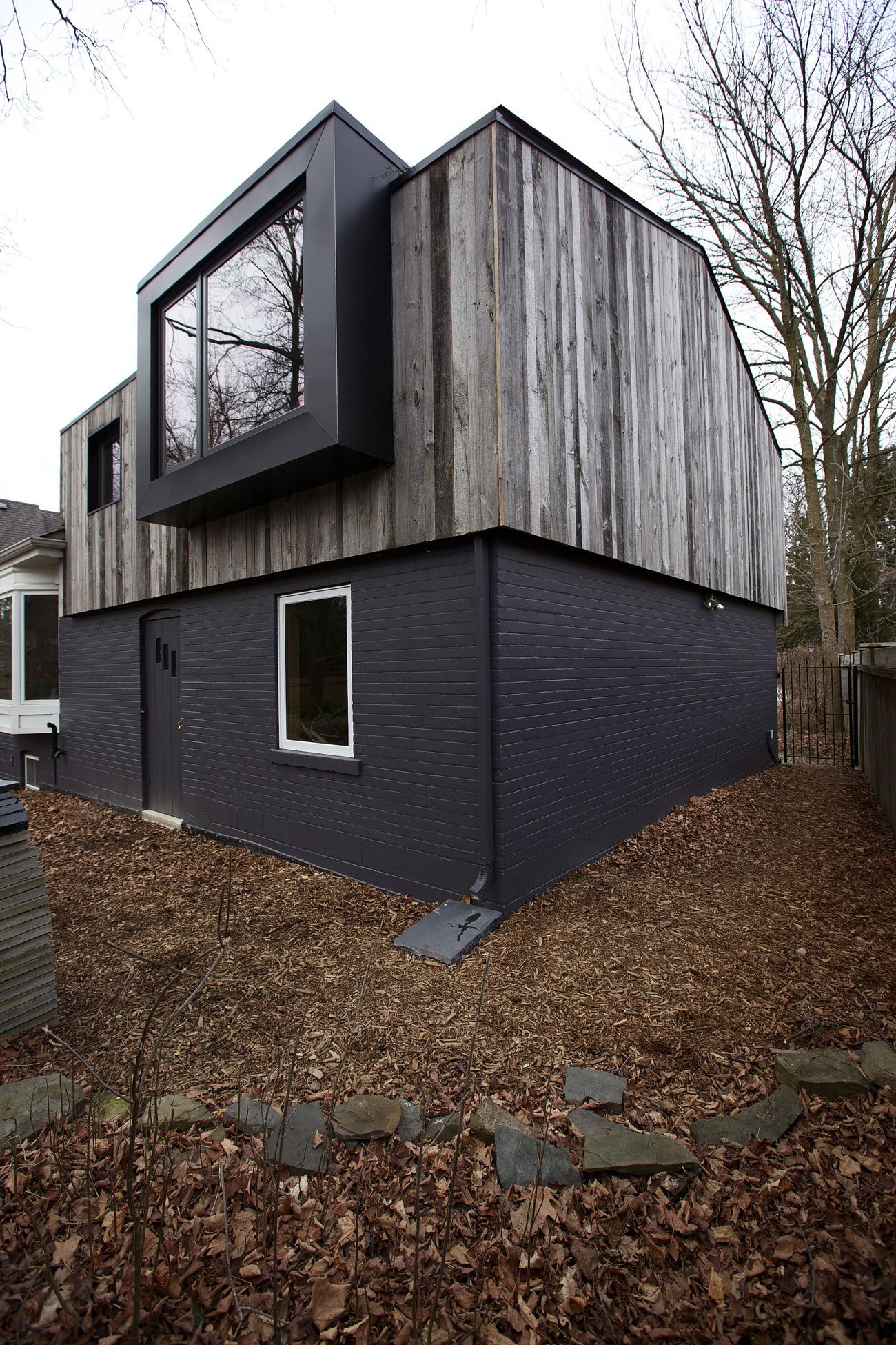 The Practice of Everyday Design Eden House Mississauga Designlines Magazine Bungalow Addition Exterior view of a cabin-inspired bungalow addition in Mississauga with a pitched roof and reclaimed barnboard siding by Design Architecture Everyday