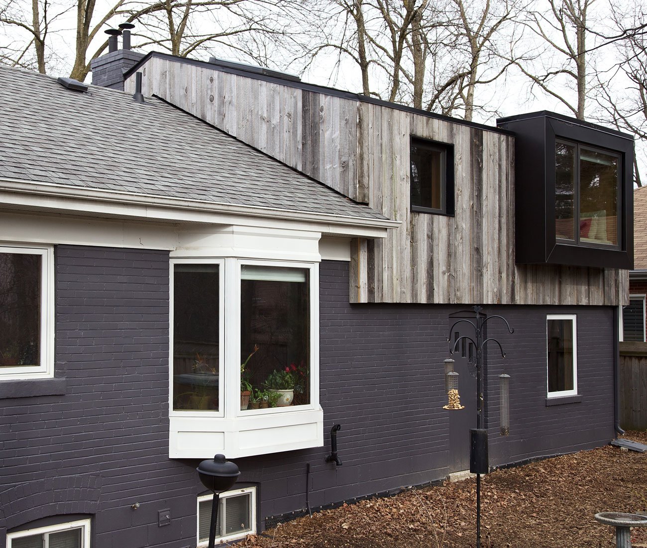 The Practice of Everyday Design Eden House Mississauga Designlines Magazine Bungalow Addition Backyard exterior view of a cabin-inspired bungalow addition in Mississauga with a pitched roof and reclaimed barnboard siding by Design Architecture Everyday