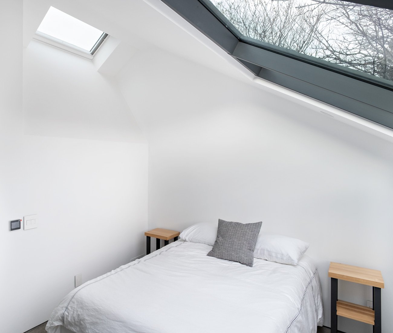 Guest bedroom with mitred glass window offering full neighborhood views; Ikea bed.
