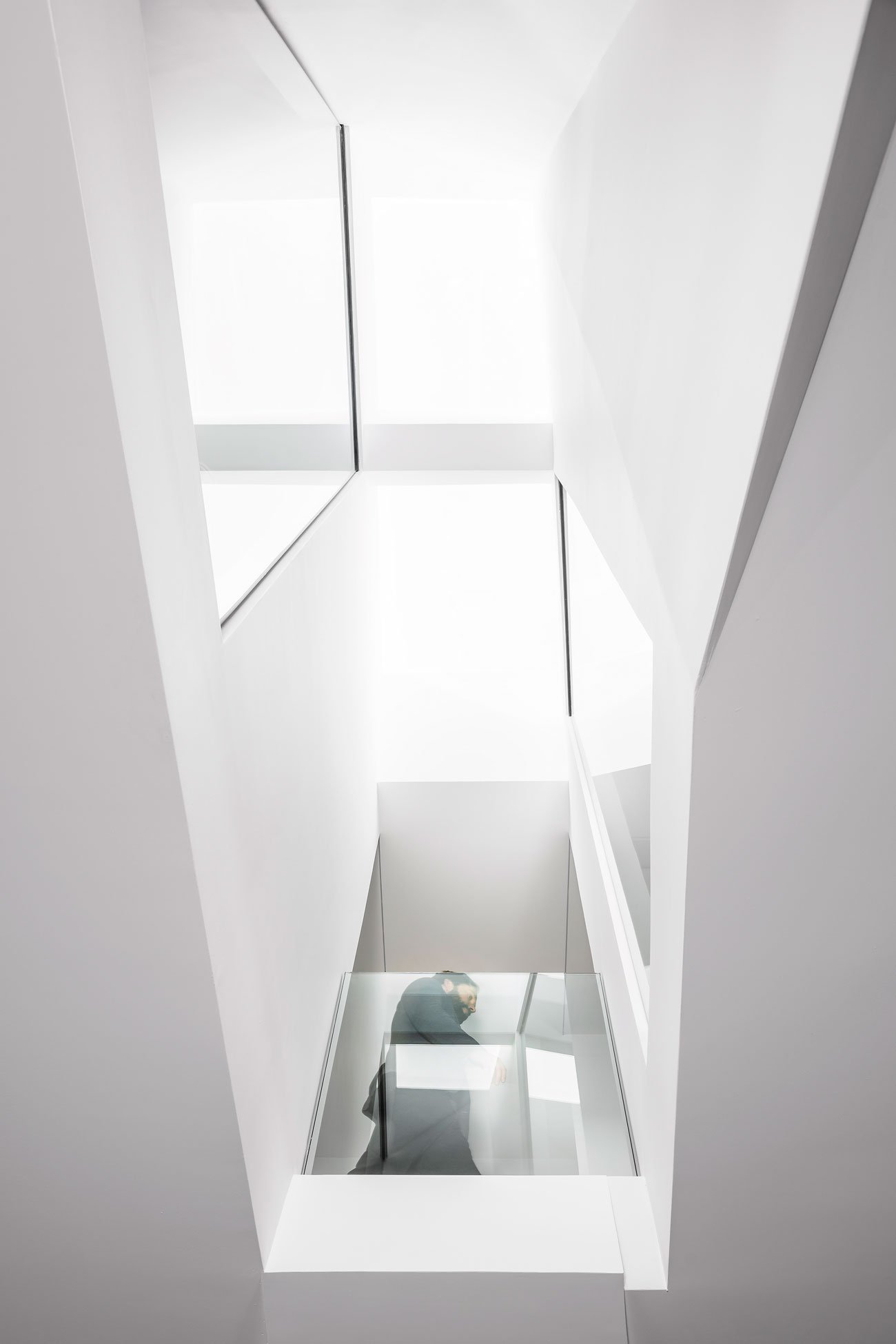 Phaedrus Studio Tesseract House Designlines Magazine Long Branch Home Staircase landing with views up to a Velux skylight, down to the first floor, and across to two staggered interior windows.