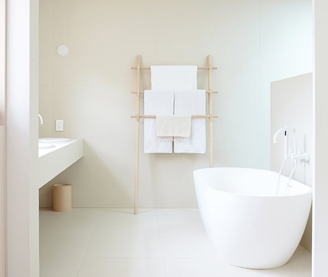 A freestanding white bathtub perfectly positioned to face a modern hanging sink, creating a sleek and minimalist bathroom vibe.