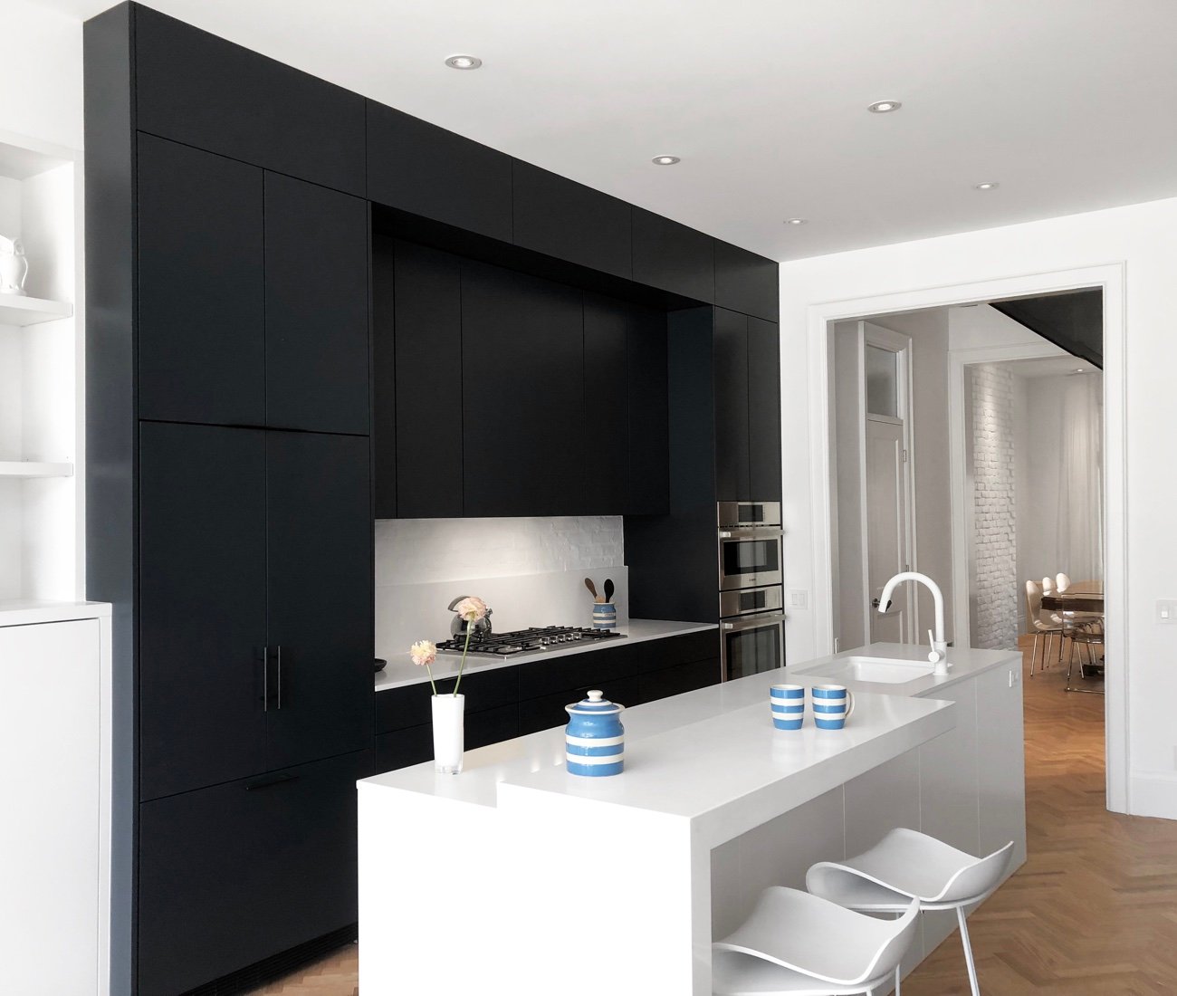 Post Architecture sleek kitchen cabinetry in blackened blue with bistro-style seating