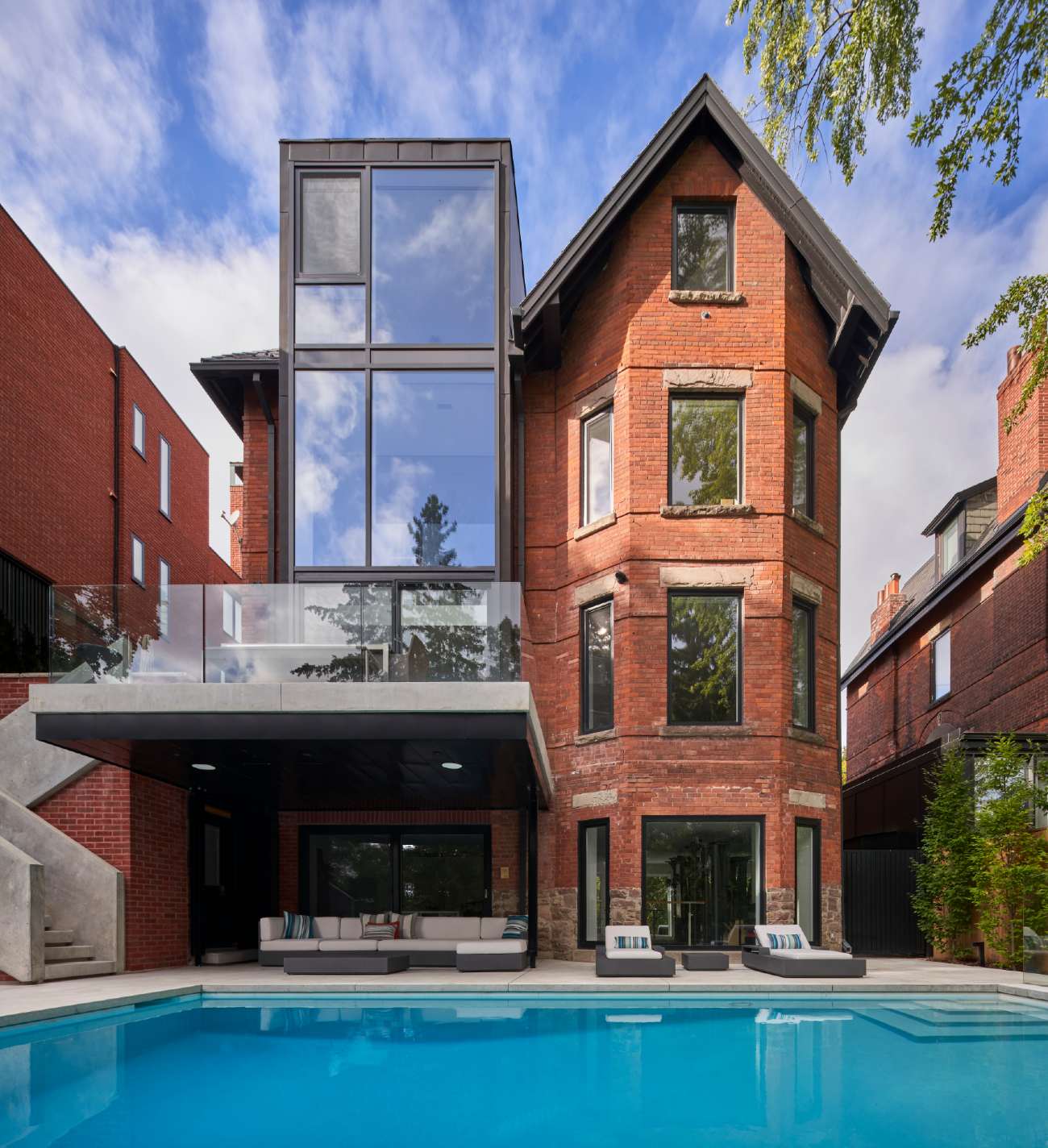 Backyard view of a newly renovated house with some patio furniture and a pool.