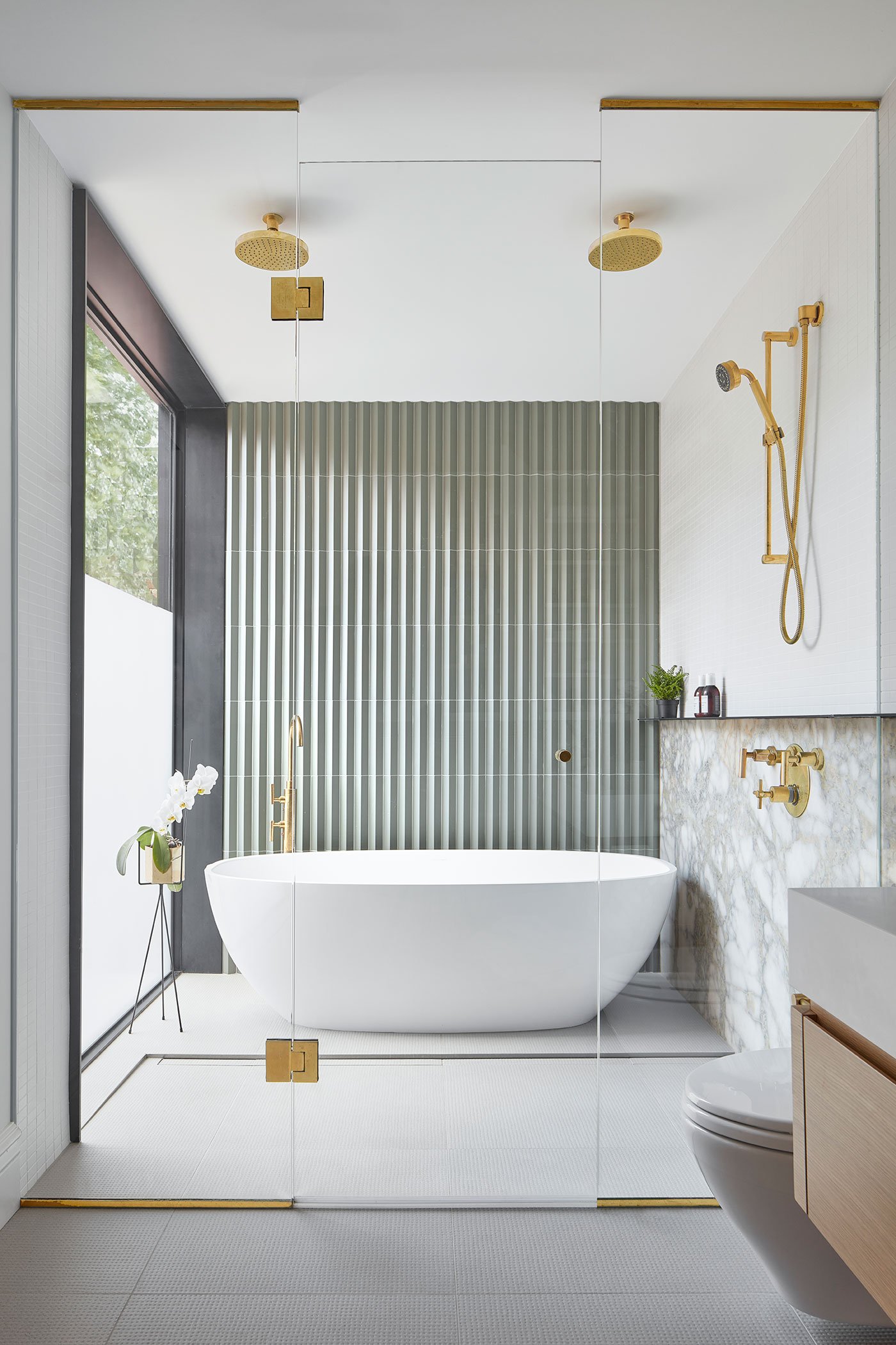 In the principal ensuite, glass doors lead into a wet area for shower and bath. Natural brass fixtures, Victoria + Albert tub, Roman Bath. Interview with Gloria Apostolou & Jennifer Kominek