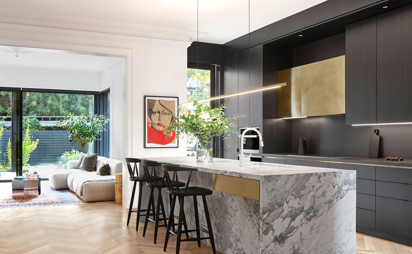 Kitchen with white oak cabinets crafted by Clarke’s Custom Woodworking and a brass exhaust hood made by Sixpenny Architectural Fabrication