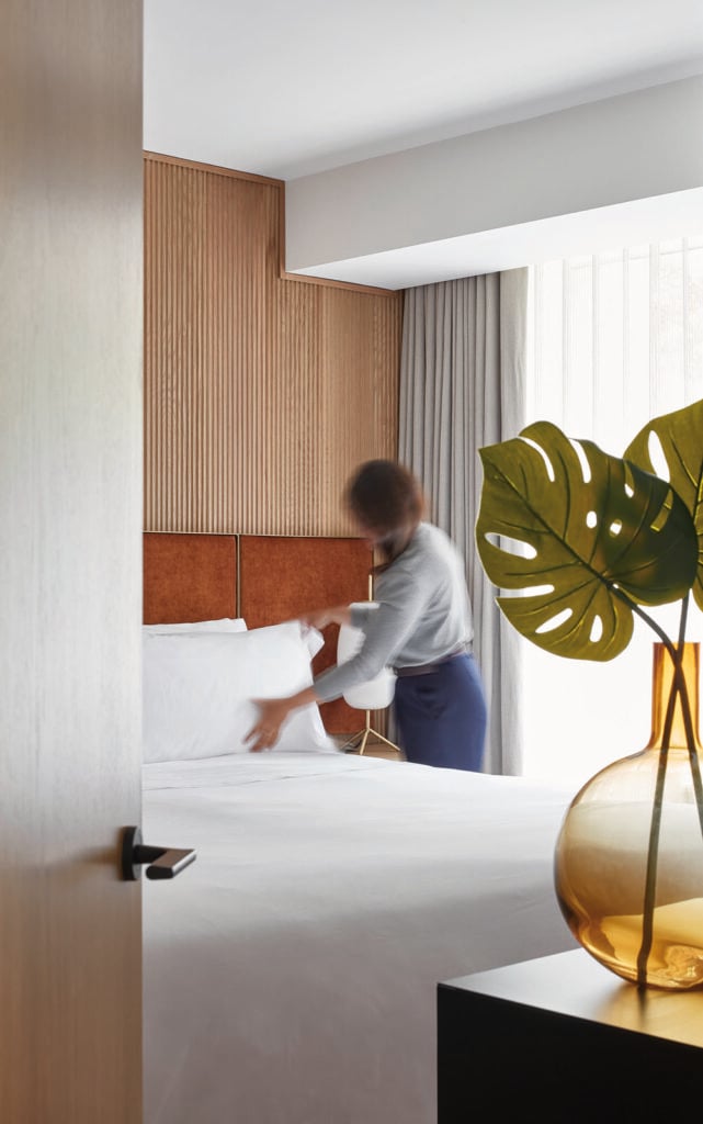 A custom headboard made of mohair fabric panels on a brass plated frame anchors the space at Manulife Centre designed by Alison McNeil