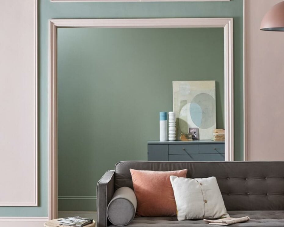 Interior living room with sage green and light pink walls with green sofa couch and accent pillows