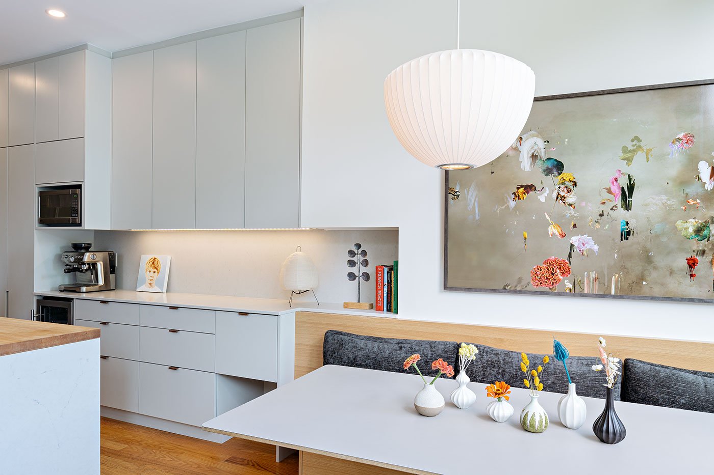 A built-in banquette anchors the kitchen-dining space. Art, Isabelle Menin; cushions, The Big Stuff; art on counter, Ben Walmsley; flowers, Euclid Farms.