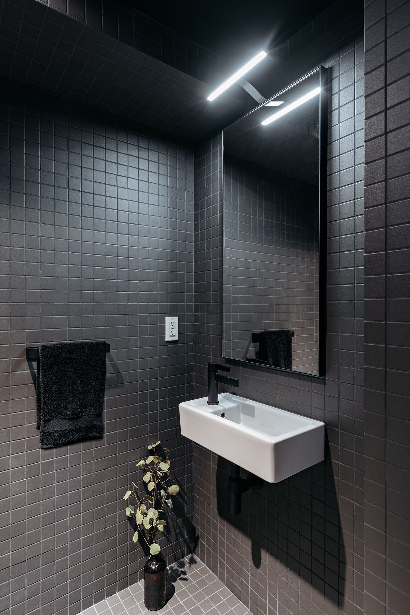 Black mosaic tile engulfs the laneway house powder room